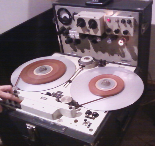 Spinning takeup reel of old analog reel-to reel audio tape recorder. Form  of magnetic tape audio recorder in which the recording medium is held on a  reel that is not in a